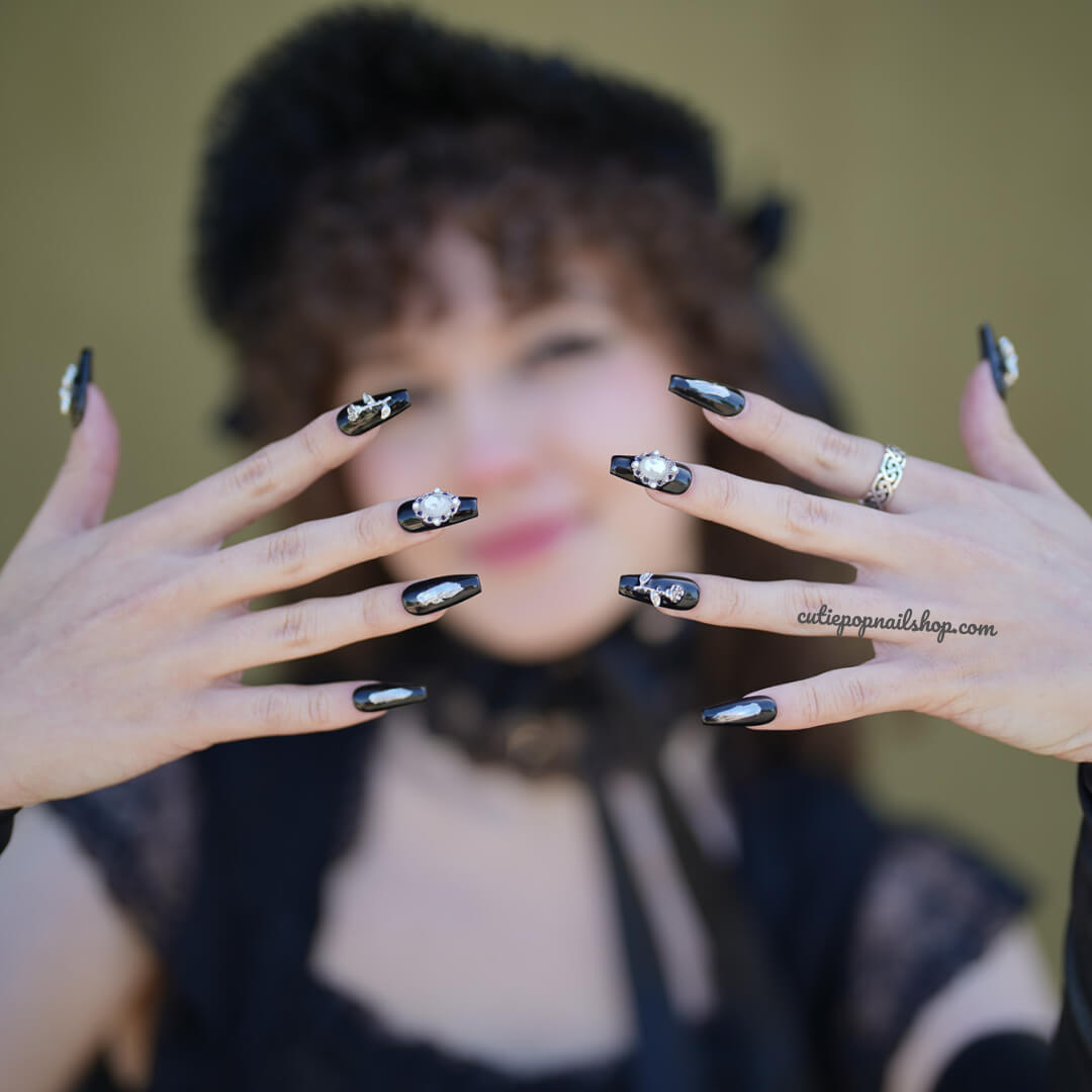 Black butterfly press-on nails by Cutie Pop Nail Shop, showcasing sleek black design with butterfly accents on artificial nail tips.