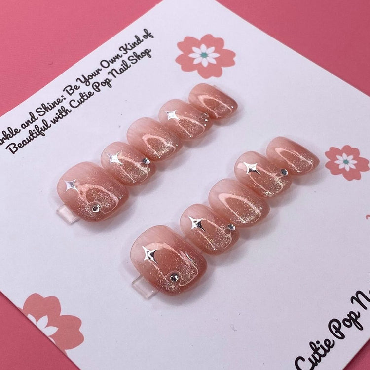 Glittery blush-colored press-on nails from Cutie Pop Nail Shop, showcasing a shiny, glamorous nail design.