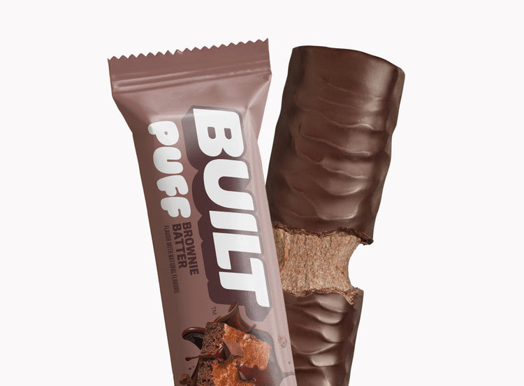 Built Brownie Batter Puff, a chocolate-flavored protein snack with a soft puff texture, stacked and ready to enjoy.
