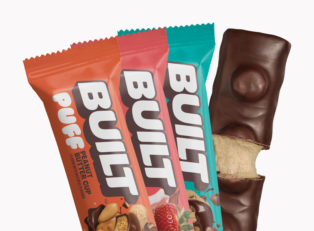 Assorted BUILT mixed snack box with various flavors in a stacked display, featuring individually wrapped puffs and snacks.
