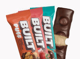 Assorted BUILT mixed snack box with various flavors in a stacked display, featuring individually wrapped puffs and snacks.