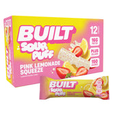 Stack of 12 BUILT Pink Lemonade Sour Puffs in a carton, showing the colorful sour candy puffs from an angled view.