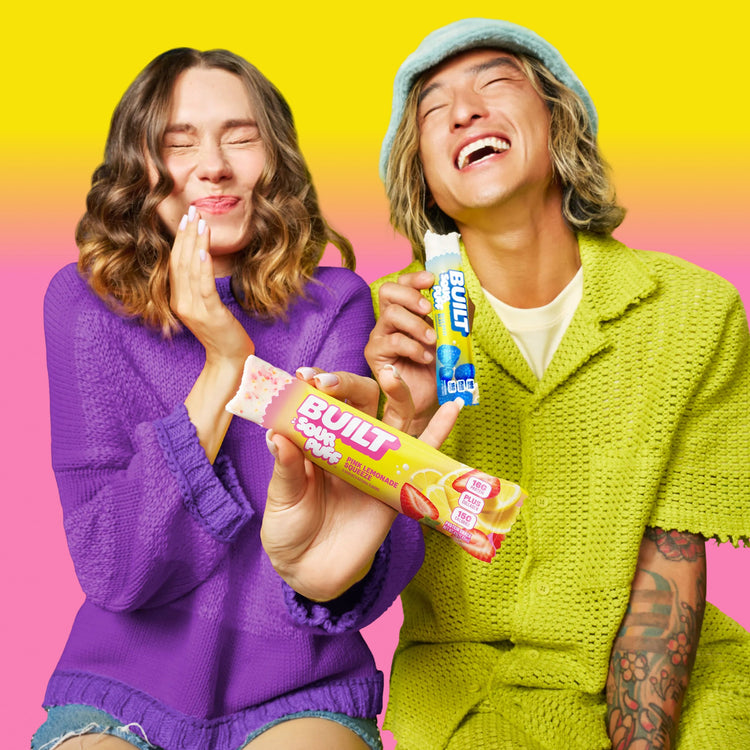 Stack of BUILT Pink Lemonade Sour Puffs, colorful sour candy puffs with pink lemonade flavor, on a lifestyle background.