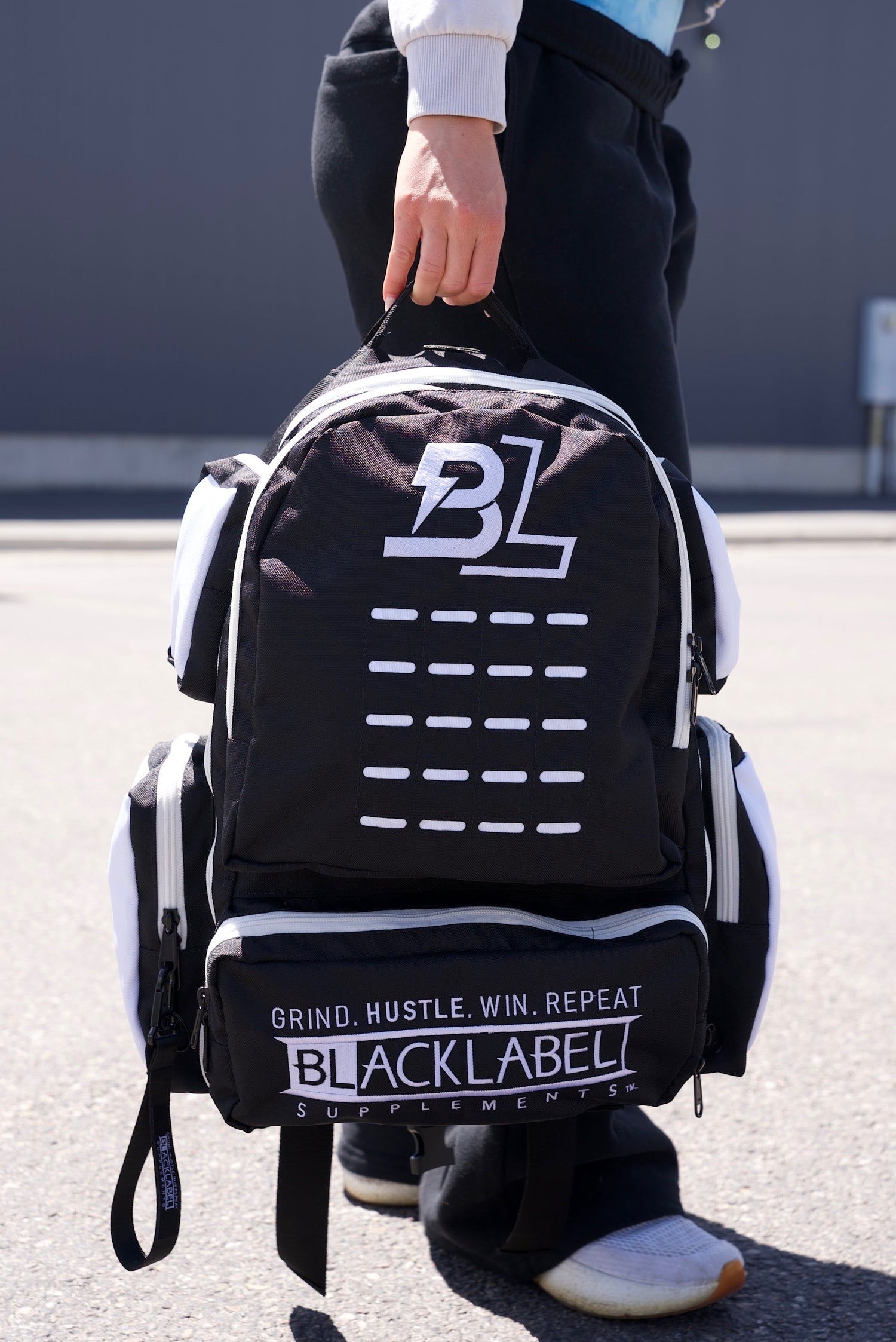 BlackLabel 26L backpack from BLACKLABEL Supplements, black nylon material with adjustable straps and multiple compartments.