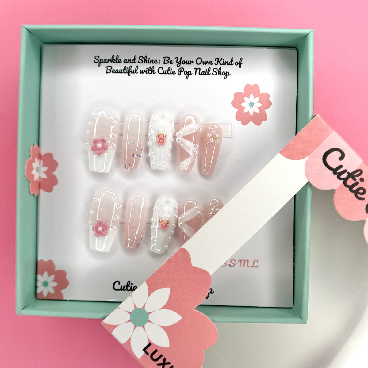 Medium coffin press-on nails by Cutie Pop Nail Shop featuring white ribbons and pink flower designs.
