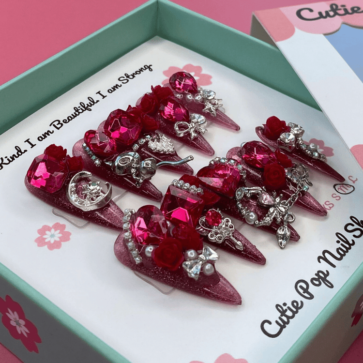 Long stiletto press-on nails with glittery Bougie Bling 11 design by Cutie Pop Nail Shop, showcasing shiny, glamorous nail tips.