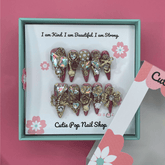 Long stiletto press-on nails with Bougie Bling design from Cutie Pop Nail Shop, featuring glittering embellishments.