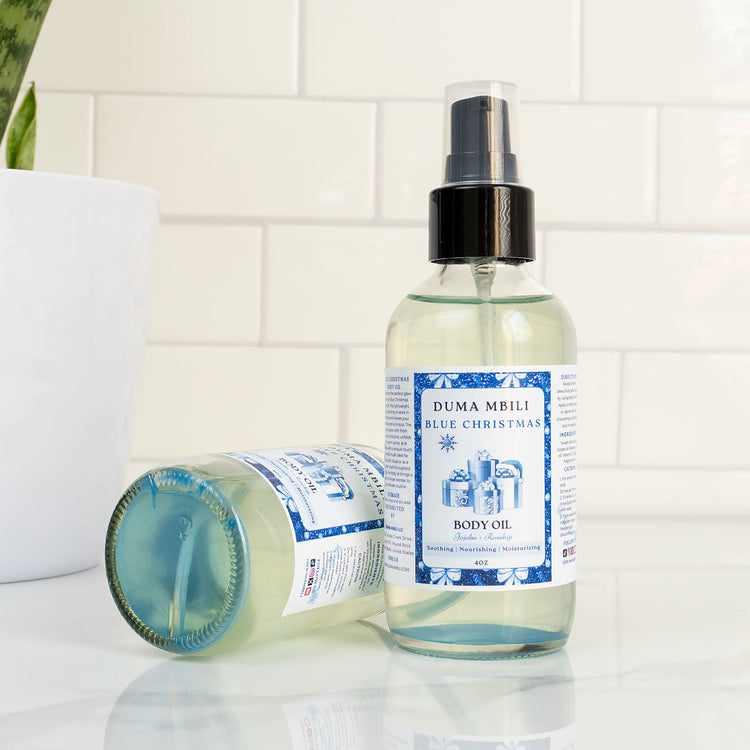 Blue Christmas Body Oil by Duma Mbili LLC in a 4 oz bottle, featuring a vibrant blue color and holiday-themed packaging.