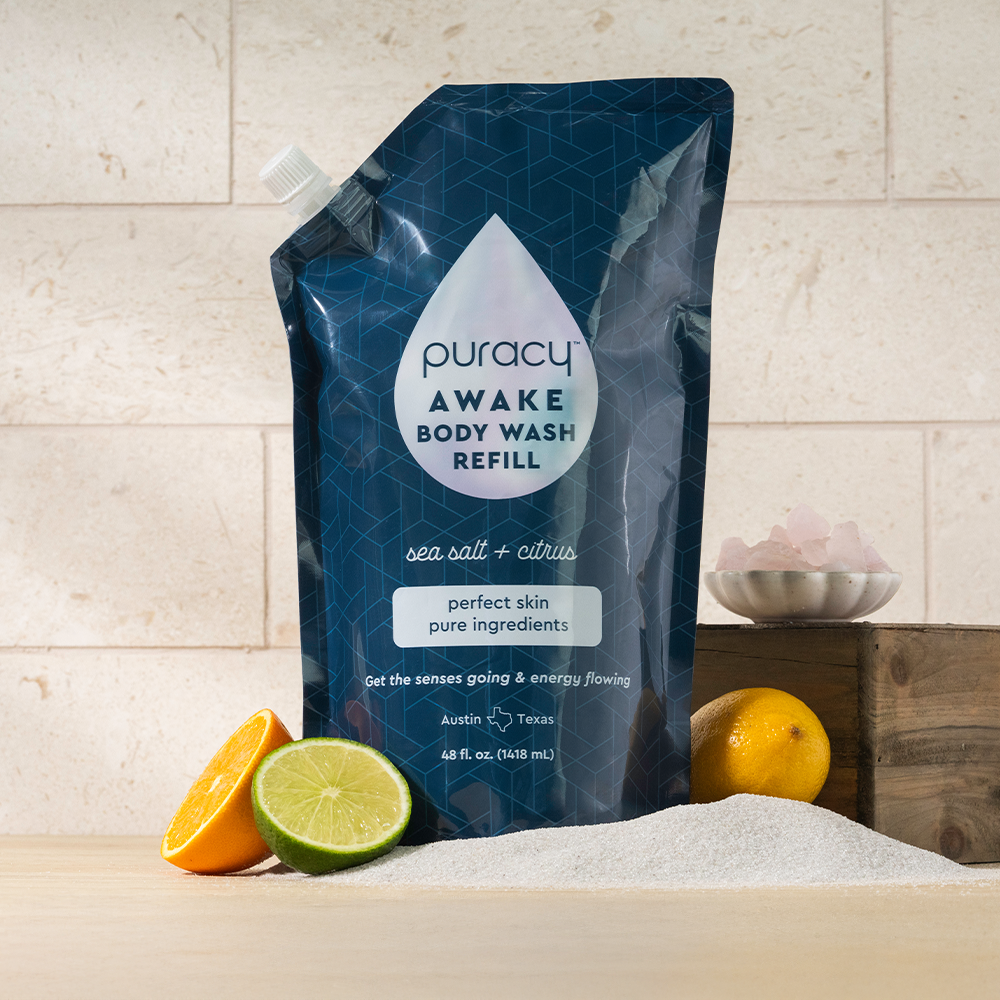 Puracy acidified, pH balanced citrus and sea salt body wash in a clear bottle, with fresh citrus slices and sea salt crystals visible