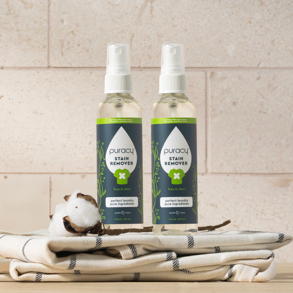 Puracy unscented laundry stain remover bottle showing stain removal action on fabric in a natural setting