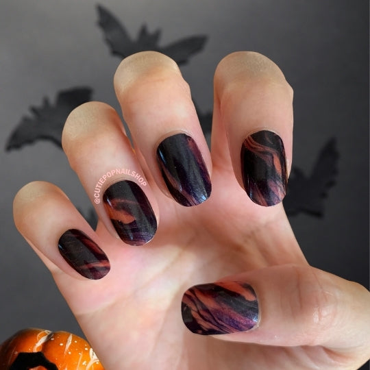Red and black smoke-inspired Cutie Pop Nail Shop Inferno nail strips applied on nails, showcasing fiery, artistic nail art design.