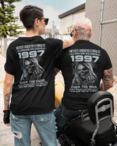 Black T-shirt from TEELUVS.COM with "Never Underestimate Us 1997" graphic, featuring a casual fit and soft cotton fabric.